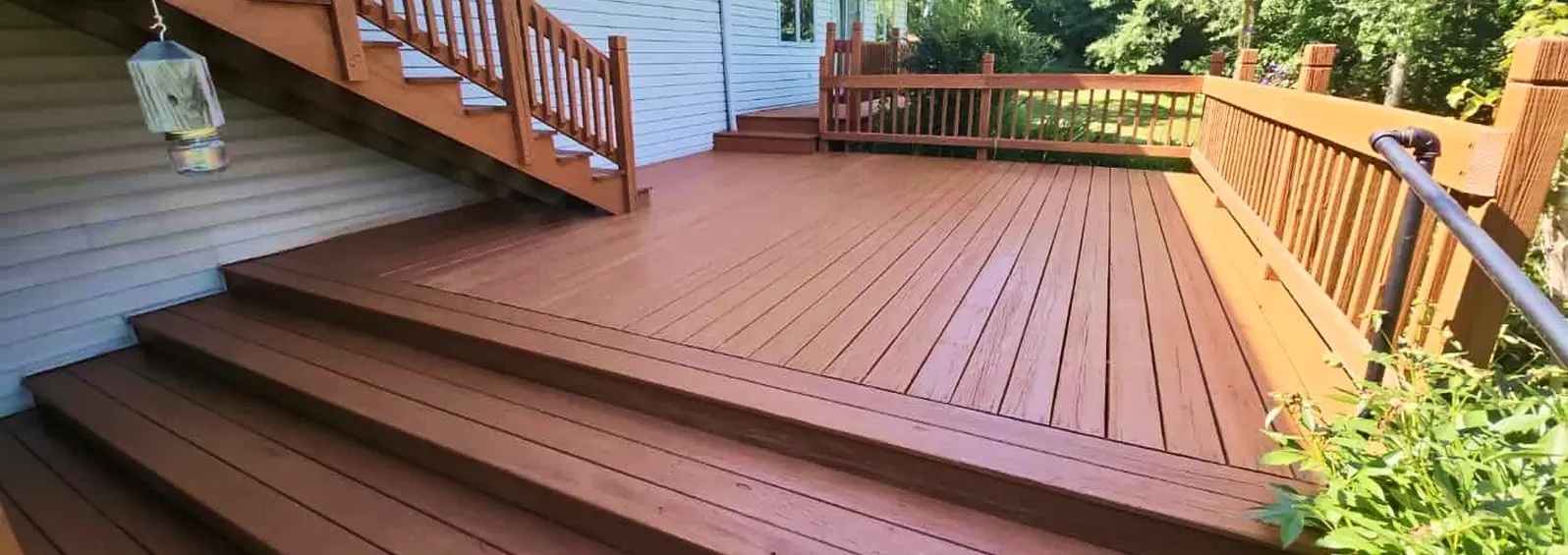 Multi-level backyard deck finished with a warm red wood stain and railings