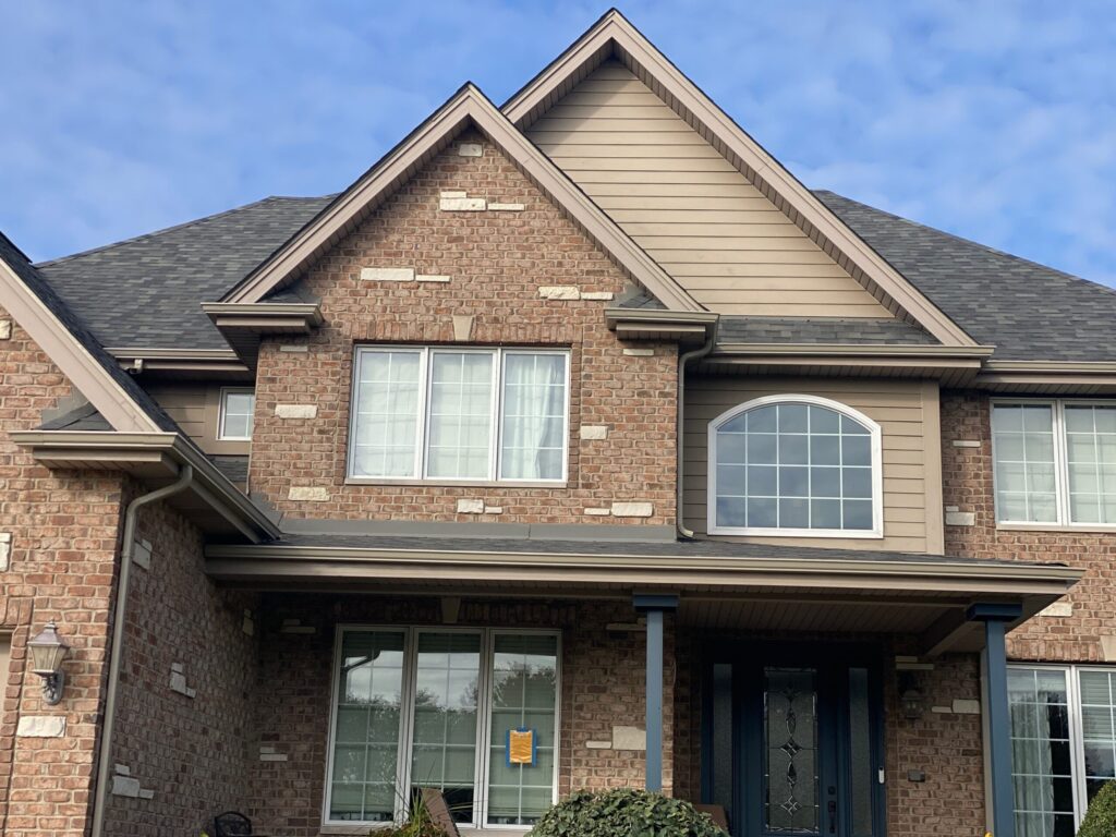 Large brick and stone home with tan trim inspected before exterior painting