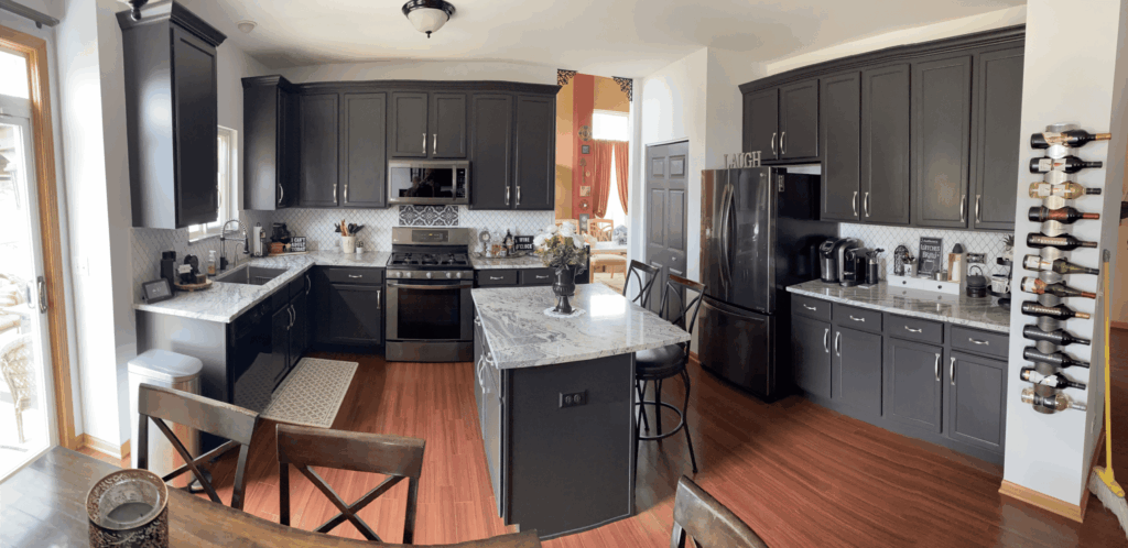 Charcoal painted kitchen cabinets paired with a white island and granite counters