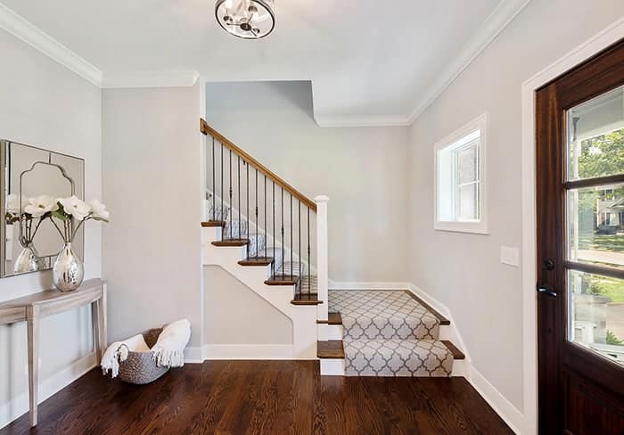 Entryway with freshly painted white walls and a staircase with patterned runner