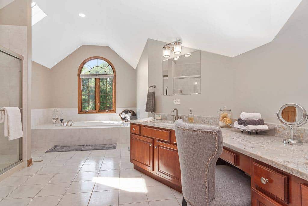Spa style bathroom with a soaking tub, wood vanity and arched window