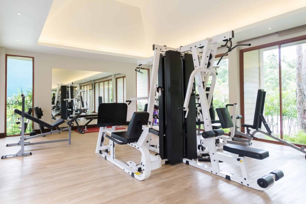 Fitness room with white painted walls and exercise equipment along tall windows