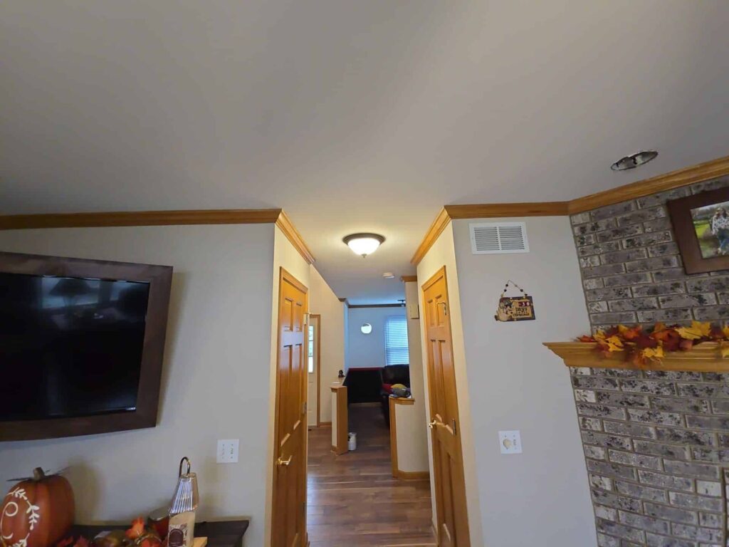 Interior hallway with beige walls, a stone accent wall and wood trim