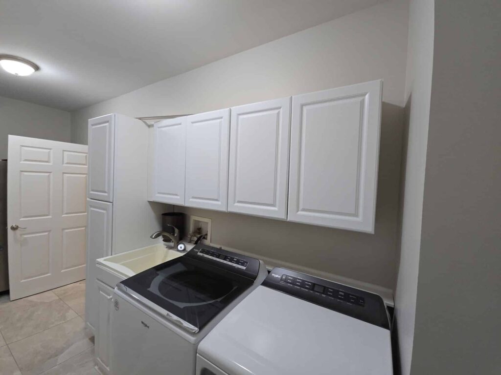 Laundry room with white painted cabinets above a washer and dryer