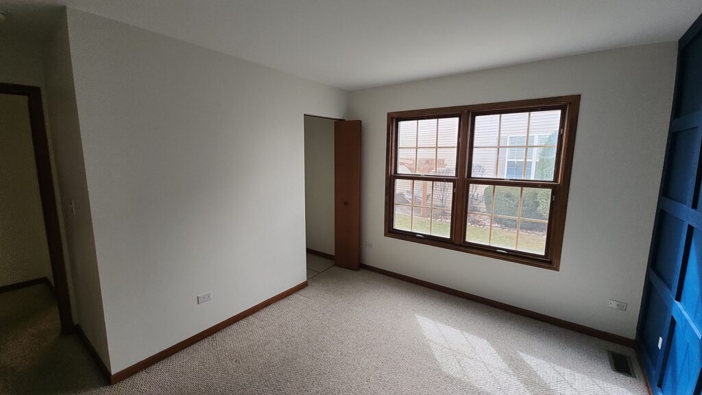 Empty bedroom with white low-VOC wall paint and a wood trimmed window