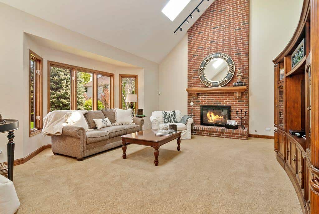 Living room with a vaulted ceiling, brick fireplace and neutral painted walls