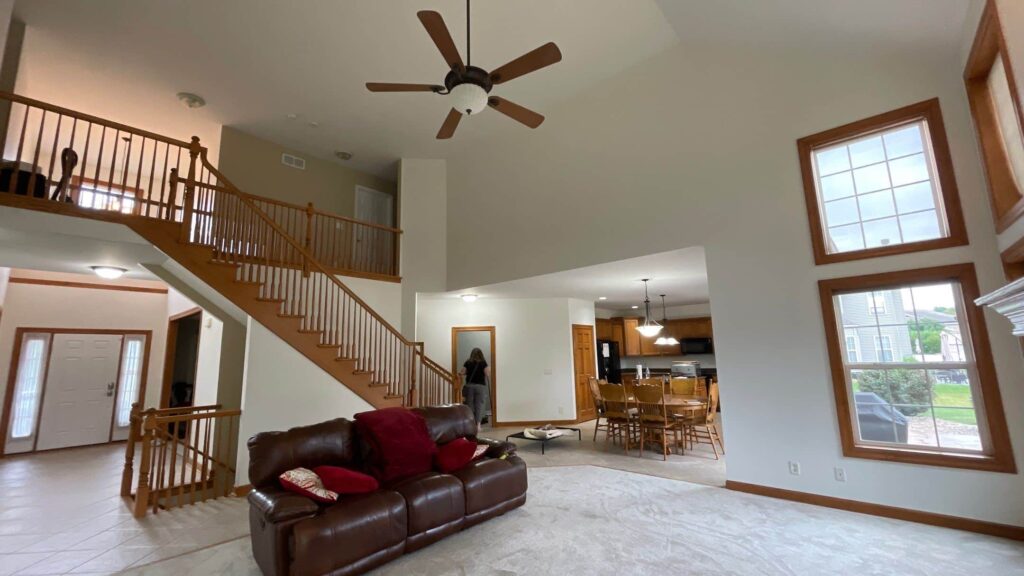 Open concept living room with white walls, a two-story ceiling and wood staircase