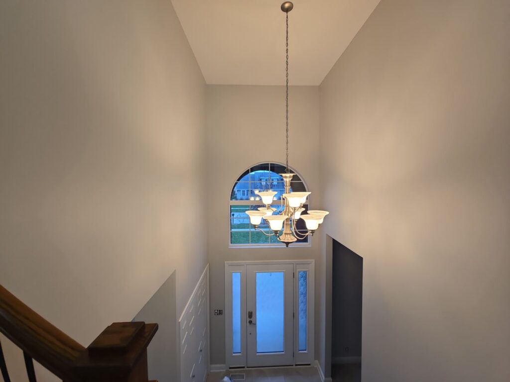 Two-story foyer refreshed with neutral paint under an arched window and chandelier