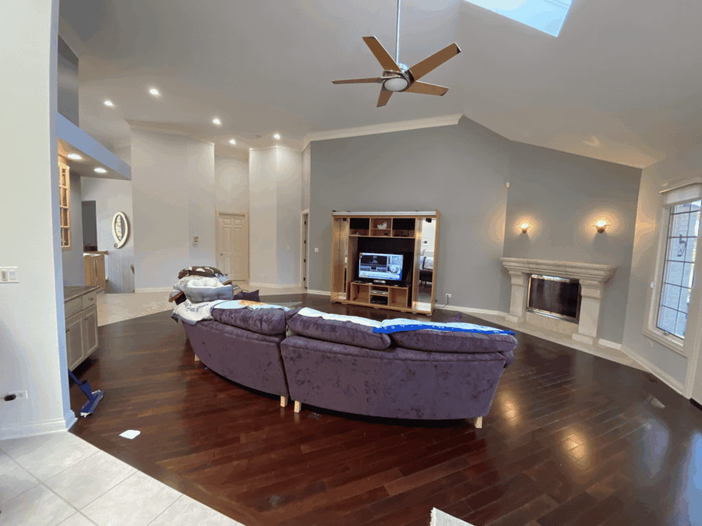 Vaulted living room with white painted walls, a fireplace and hardwood floors