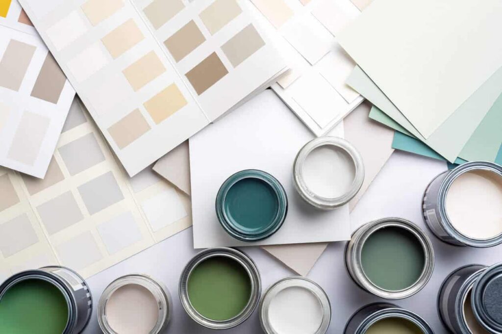 Open paint cans and color swatch cards in green, beige and teal tones