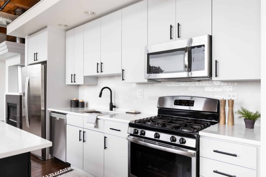 White painted kitchen cabinets with black hardware and stainless steel appliances
