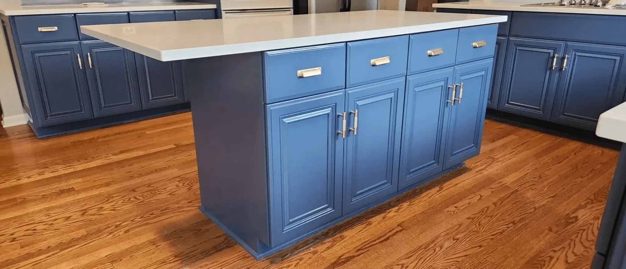 Navy blue kitchen island with brushed nickel hardware and white countertop after cabinet painting