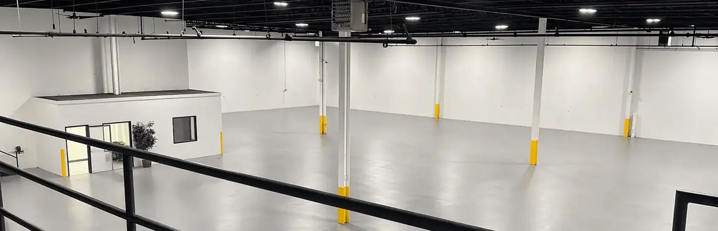 Freshly painted warehouse interior with white walls and yellow safety bollards in Carol Stream, Illinois