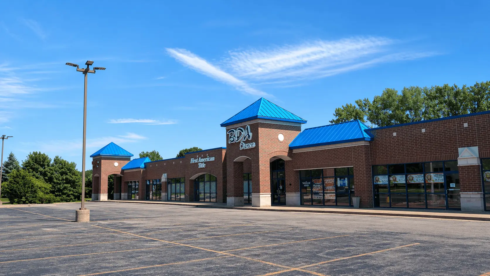 Repainted brick retail strip mall with blue awnings at a commercial painting project in Joliet, Illinois