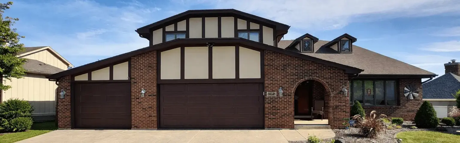 Brick and stucco Tudor-style home with repainted brown garage doors in Lockport, Illinois