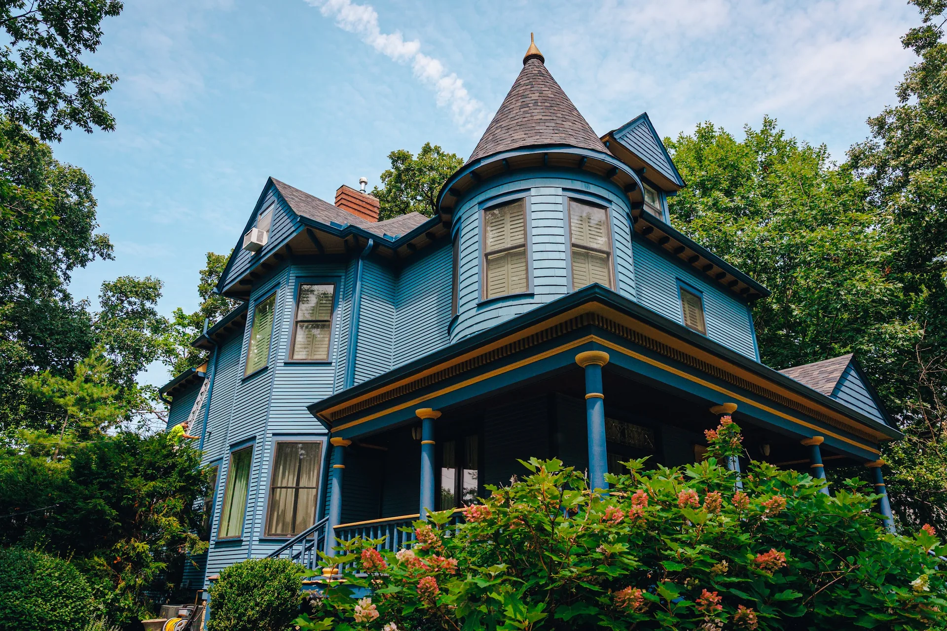 Side view of a blue Victorian home with a turret after exterior painting
